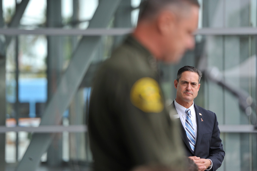 Orange County Supervisor Todd Spitzer listens as Undersheriff Don Barnes, of the Orange County Sheriff’s Department, during an event earlier this year. Spitzer wants the department to change a policy that allows deputies to continue working on patrol even if they face a criminal investigation.